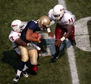 A tackle in a college football game between the Naval Academy and the University of Massachusetts