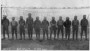 Gas mask-wearing British soldiers in front of a soccer goal in 1916