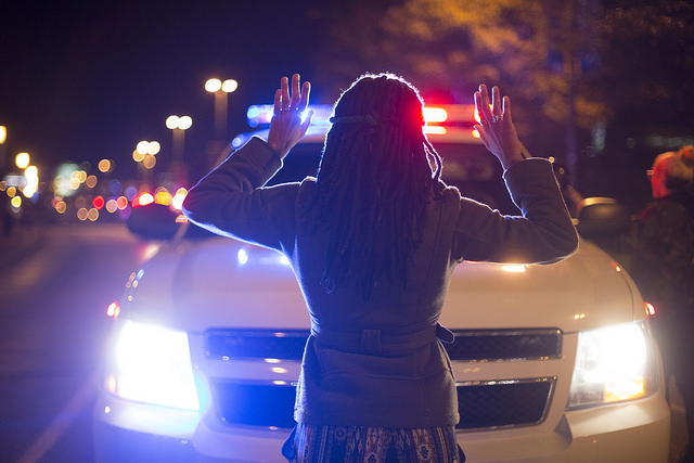 Woman holding her hands up in front of a police car at a Ferguson protest