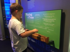 Isaiah playing a primitive dulcimer